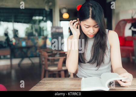 Profitez de moments de détente avec la lecture de livres de belles femmes asiatiques Thai teen lire un livre dans le ton des couleurs vintage coffee shop Banque D'Images