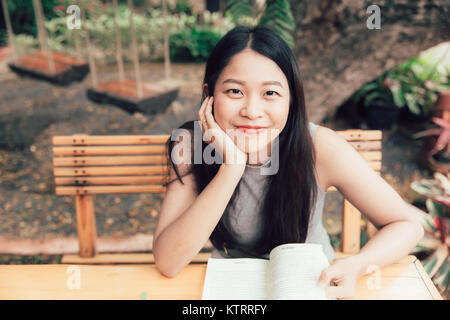 Profitez de moments de détente avec lecture du livre, les femmes asiatiques Thai teen sourire avec réserve en coffee shop vintage color tone Banque D'Images