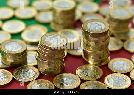 Un grand nombre de pièces d'une livre sur un fond vert et rouge dans les tas d'argent. Beaucoup d'argent en espèces et des piles piles sur une carte colorée et Banque D'Images