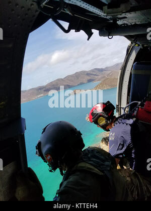 L'enquête sur la destruction de l'équipage de l'hélicoptère au-dessus des îles Vierges américaines. Aviateurs de la New York Air National Guard's 106th Rescue Wing voler plus de Saint-Thomas et Saint-John dans un HH-60 Pave Hawk helicopter le 10 septembre, 2017. Ils cherchent des personnes qui ont besoin d'une aide indispensable à la suite de l'ouragan l'Irma. Banque D'Images