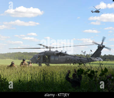 Les cavaliers de sauveteurs-parachutistes du 103e Escadron de sauvetage une sortie U.S. Air Force HH-60 Pave Hawk helicopter et se préparer à prendre deux personnes isolées durant la grève 16 Sabre à la base aérienne d'Amari, l'Estonie le 14 juin 2016. Grève de sabre est un exercice multinational qui teste les capacités de divers aspects de l'armée impliqués. (U.S. Air National Guard photo/Le s.. Blake Mize) Banque D'Images