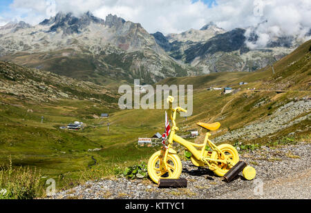 Image d'un petit vélo jaune dans les Alpes à proximité d'une route où les cyclistes du Tour de France va passer. Banque D'Images