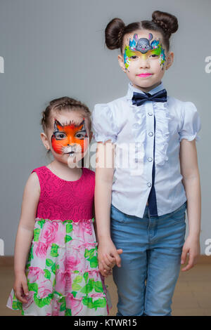 Les petites filles soeur avec rasskrashennymi visages isolé sur fond gris Banque D'Images