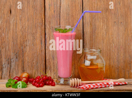 Smoothie aux petits fruits, groseilles, groseilles à maquereau et le miel sur une surface en bois Banque D'Images