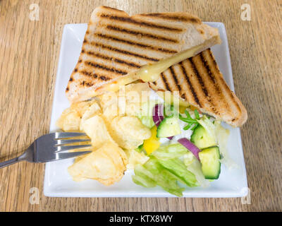 Bonne collation au déjeuner fromage grillé et tomates en sandwich dans du pain blanc avec de la salade et chips de pommes de terre Banque D'Images