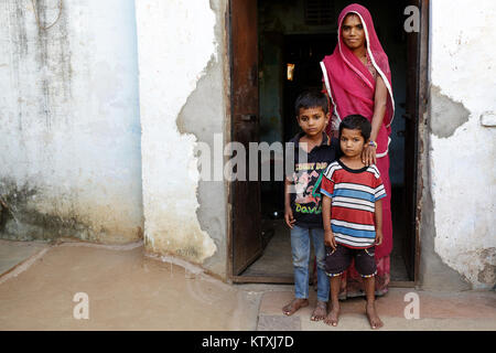 Jeune femme indienne sari et porter un voile sur ses cheveux avec ses enfants à la porte à leur accueil, village près de Pushkar, Rajasthan, Inde. Banque D'Images