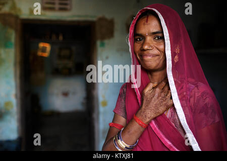 Portrait of smiling young woman wearing sari et un voile sur ses cheveux dans sa maison, village près de Pushkar, Rajasthan, Inde. Banque D'Images