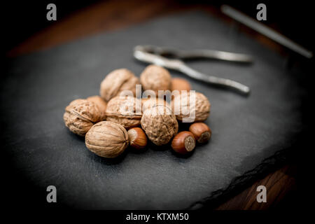 Fruits entiers mixtes dans leurs coquilles, y compris les noix, noisettes, amandes et noix de pécan avec un nut cracker Banque D'Images