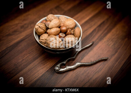 Un bol de fruits entiers mixtes dans leurs coquilles, y compris les noix, noisettes, amandes et noix de pécan avec nut cracker Banque D'Images