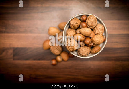 Un bol de fruits entiers mixtes en bonne santé dans leurs coquilles, y compris les noix, noisettes, amandes et noix de pécan en plongée des Banque D'Images