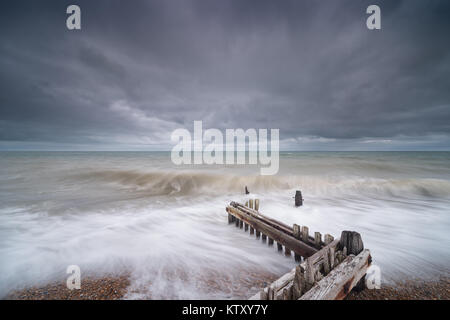 Rustique en épi à Rye, East Sussex coast, avec des vagues déferlaient sur elle. Ciel d'orage à destination. Banque D'Images