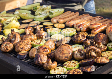 Un assortiment de délicieuses grillades avec les légumes sur le barbecue sur le fusain. Saucisses, steaks, poivre, champignons, courgettes. Banque D'Images