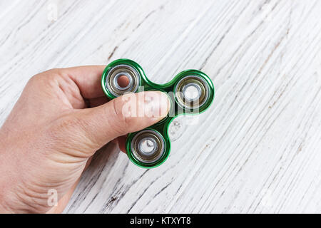 Main Garçon jouant avec fidget spinner gadget. Vert main spinner, agitait la main en rotation jouet sur l'homme de main. Banque D'Images