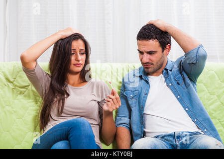 Jeune couple est à la recherche de test de grossesse positif. Ils sont bouleversés et inquiets. Banque D'Images