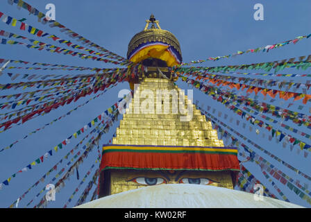 Haut de la Bodnath stupa bouddhiste : le dôme doré et les yeux de Bouddha sous lui, la prière des drapeaux tibétains dans différentes directions divergent contre Banque D'Images