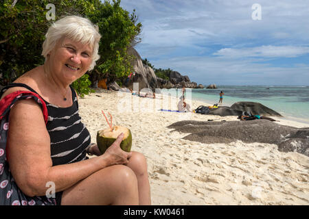 Femme à boire avec une paille et de jus de noix de coco, le lait de coco sur la plage Anse Source d'argent, La Digue, Seychelles Banque D'Images