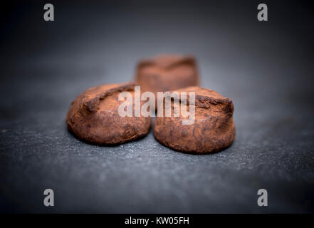 Délicieux, délicieux et savoureux faits maison truffes au chocolat de luxe reposant sur un arrière-plan en ardoise noire Banque D'Images