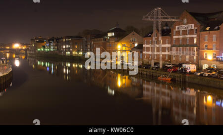 York, England, UK - 28 janvier 2017 : Entrepôts avec des grues et des immeubles d'appartements moderne line les quais de la rivière Ouse dans la nuit de New York. Banque D'Images