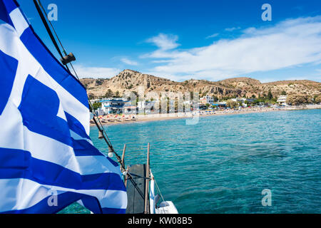 Avis de drapeau grec sur le bateau et la plage de Stegna behaind (Rhodes, Grèce) Banque D'Images