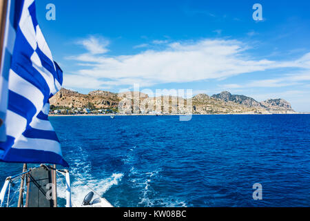 Avis de drapeau grec sur le bateau et la plage de Stegna behaind (Rhodes, Grèce) Banque D'Images