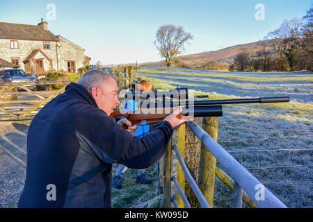 L'homme et adolescent tiré un fusil sur les terres agricoles sur l'air froid, un jour froid. Banque D'Images