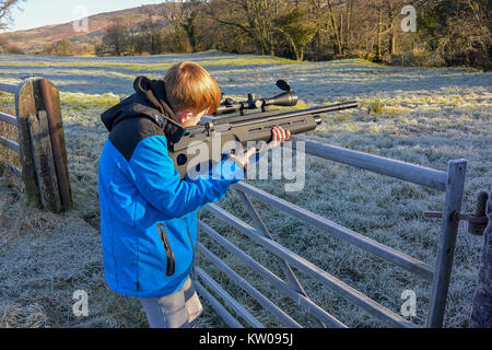 Teenage boy tiré un fusil sur les terres agricoles sur l'air froid, un jour froid. Banque D'Images