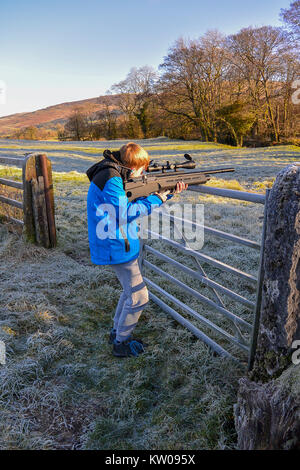 Teenage boy tiré un fusil sur les terres agricoles sur l'air froid, un jour froid. Banque D'Images