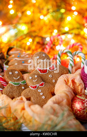 Biscuits au gingembre sous la forme de petits hommes à l'arrière de guirlandes de couleur rougeoyante. Noël et ses décorations. Bannière pour le site de Noël. Banque D'Images