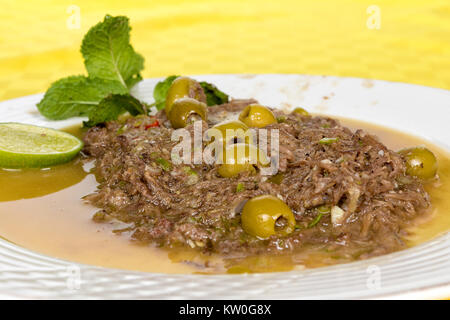 La viande de veau arraché servi dans un plat blanc mariné aux olives, et d'un extracteur à jus de citron Banque D'Images