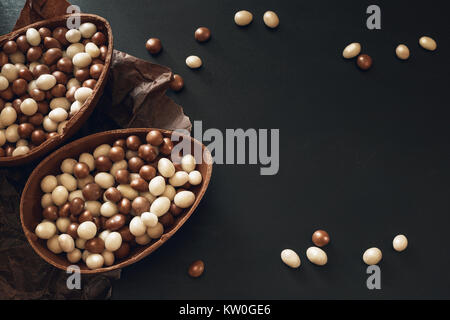 Oeufs de Pâques en chocolat plein de bonbons sur fond sombre Banque D'Images