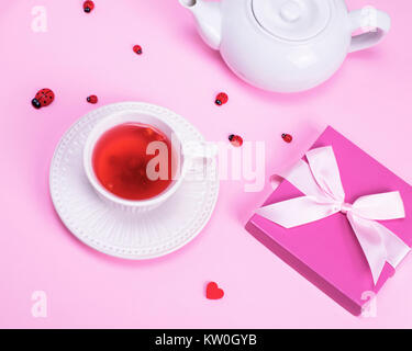 Plateau à partir des baies de viburnum dans une tasse en céramique blanche et fort avec un cadeau sur fond rose Banque D'Images