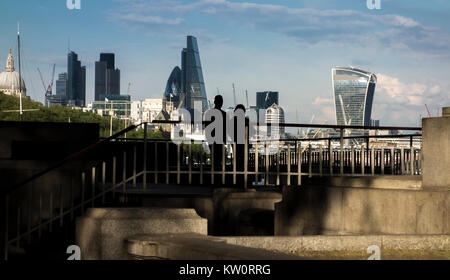 Couple regarder vers la ville de Londres à partir d'une plate-forme d'observation sur la rive nord de la Tamise en vertu de Waterloo Bridge, London, UK Banque D'Images