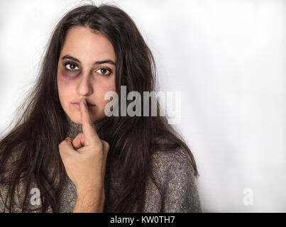 La neutralisation de l'agresseur à sa victime, une jolie femme noire avec un œil meurtri, avec son doigt dans un concept de violence domestique et d'abus, avec copie espace sur Banque D'Images