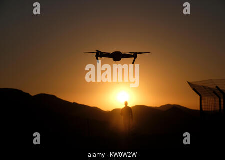 Un appareil radio controlled quadcopter drone survolant une silhouette d'homme debout à une position de défense de l'armée israélienne sur une colline stratégique dans l'ouest de la vallée de la plaine connue en hébreu comme Arava ou Aravah qui fait partie de la frontière entre Israël et la Jordanie. Banque D'Images