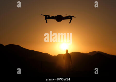 Un appareil radio controlled quadcopter drone survolant une silhouette d'homme debout à une position de défense de l'armée israélienne sur une colline stratégique dans l'ouest de la vallée de la plaine connue en hébreu comme Arava ou Aravah qui fait partie de la frontière entre Israël et la Jordanie. Banque D'Images