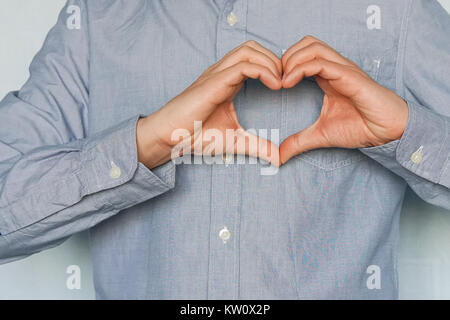 Un symbole de l'amour ne mains. Le jour de la Saint-Valentin. Un jeune homme amoureux montre ses sentiments. De coeur avec ses mains sur fond blanc, je Banque D'Images