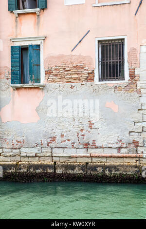 Côté d'un bâtiment sur un canal de Venise avec la maçonnerie en ruine et le rendu et de volets Banque D'Images