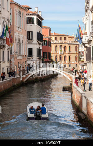 Rio San Trovaso canal in Venice occupé avec les touristes à flâner au soleil et d'un lancer qui passe sous un pont voûté Banque D'Images