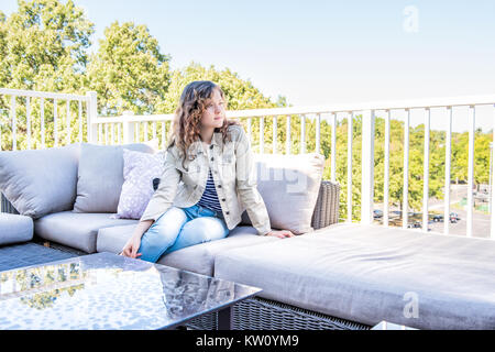 Une jeune femme assise sur la table à l'extérieur sur balcon loft dans maison, maison ou appartement Banque D'Images