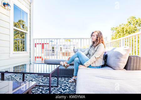 Une jeune femme assise sur la table à l'extérieur sur balcon loft dans maison, maison ou appartement Banque D'Images