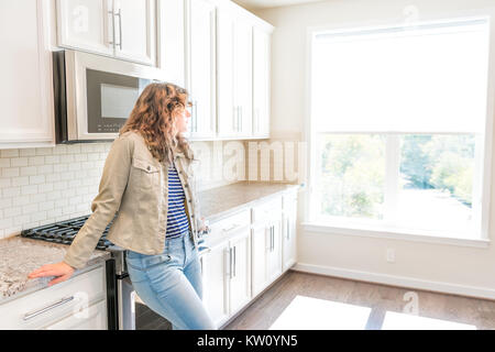 Une jeune femme debout dans la cuisine en propre, moderne, blanc accueil conception avant l'emménagement Banque D'Images