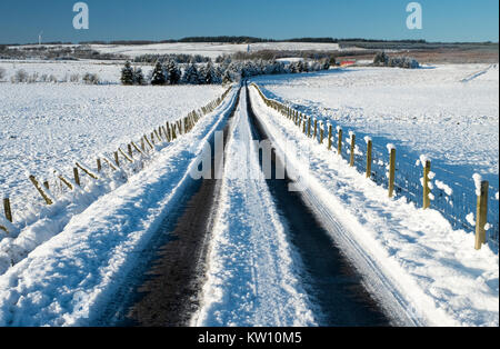 La neige a couvert retour route à travers les terres agricoles près de Forth, Lanarkshire, Écosse Banque D'Images
