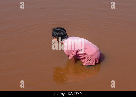 Un jeune homme khmer dans un étang de pêche Banque D'Images