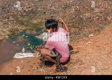 Un jeune homme khmer dans un étang de pêche Banque D'Images