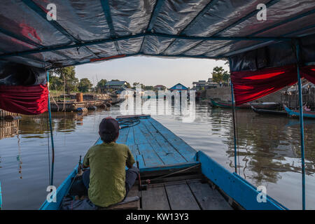 Un bateau de tourisme navigation à travers le village de pêcheurs sur le lac Tonle Sap, Cambodge Banque D'Images