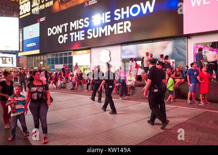 Au cours d'une vie noir Question manifestation à New York Times Square à la suite des coups de décès de Alton Sterling et Philando Castille, une femme tient son enfant par la main et regarde avec appréhension comme une ligne de New York City Police Department (NYPD) police anti-émeutes de mars à la place, 2016. Banque D'Images