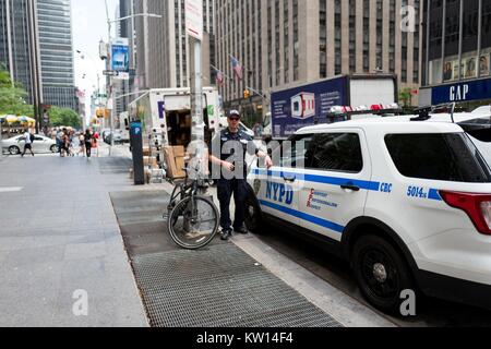 Un département de la Police de New York la lutte contre le terrorisme est à l'agent de prêt, tandis que son collègue se trouve dans un véhicule de police, sur la 6ème Avenue, Manhattan, New York City, New York, juillet 2016. Banque D'Images