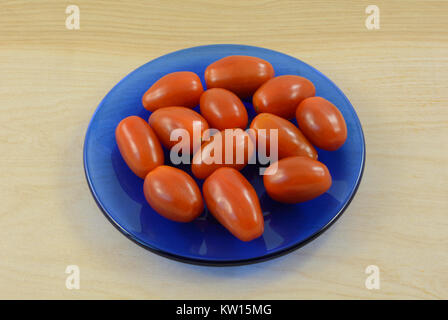 Tomates Raisins cru entier dans de petites plaque bleue sur la table en bois Banque D'Images