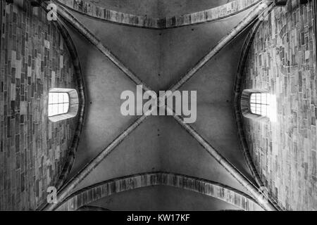 Cathédrale de voûtes en pierre de dessous avec deux fenêtre avec lumière brillant à travers. Noir et blanc. Banque D'Images