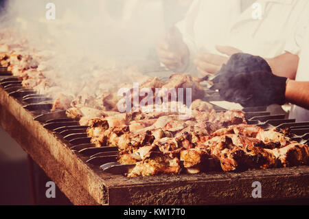 Shish kebab traditionnel. Les aliments frits sur le grill. Une délicieuse viande grillée, frite dans la nature. Caucasien mâle tenant une brochette de viande Banque D'Images